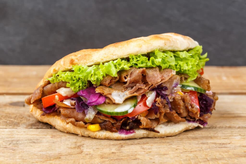 Döner kebab garni de viande grillée à la broche, crudités fraîches et sauce, servi dans un pain