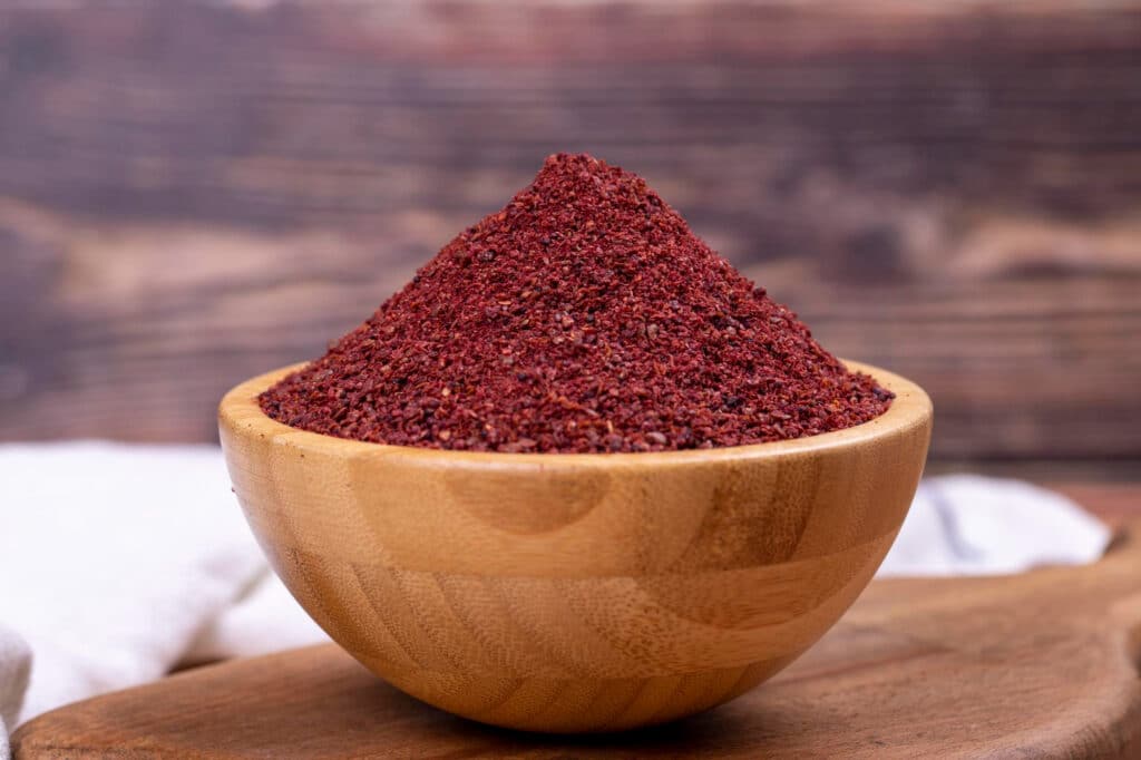 Sumac en poudre dans un bol en bois, épice rouge acidulée utilisée en cuisine orientale