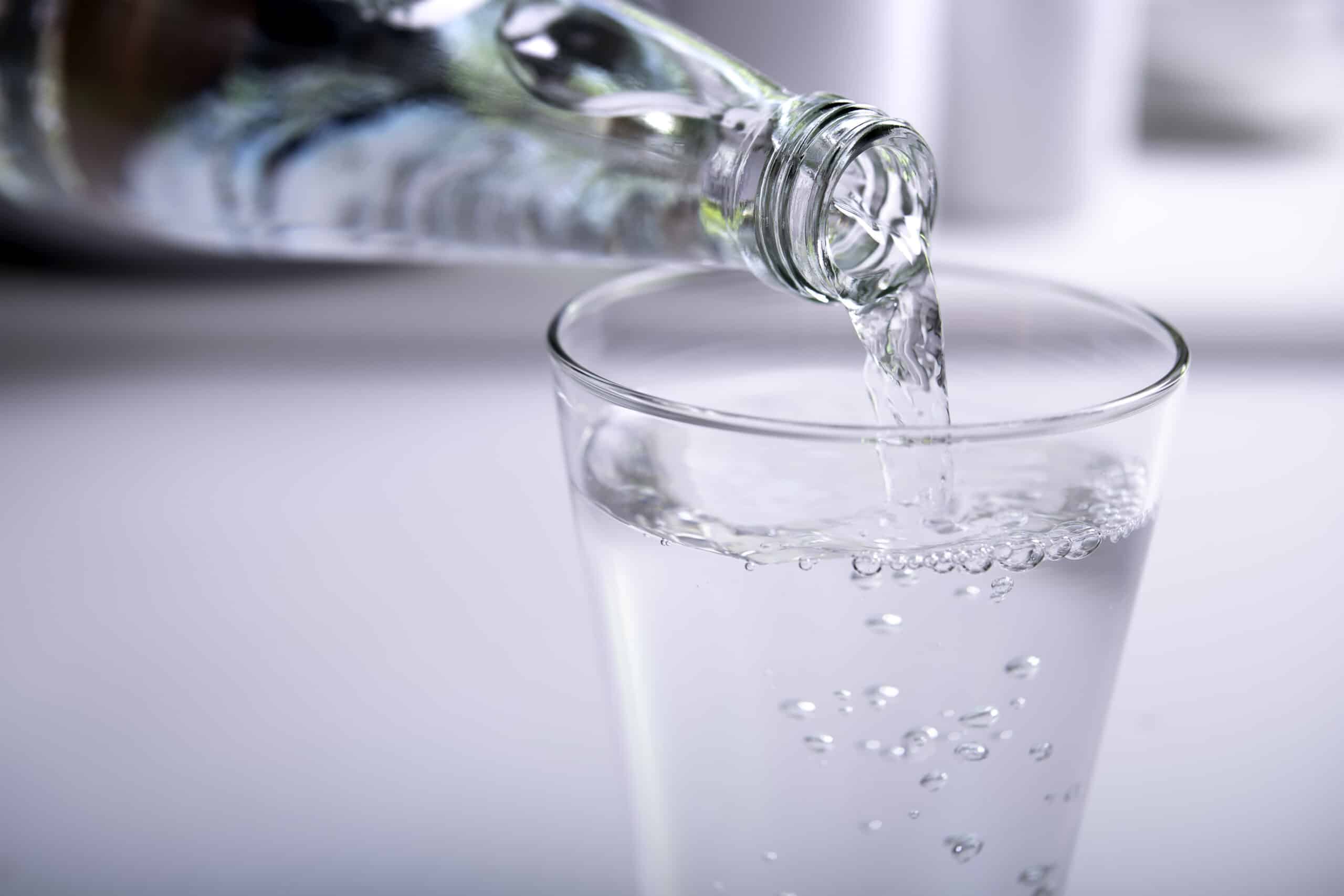 Bouteille en verre versant de l’eau dans un verre.